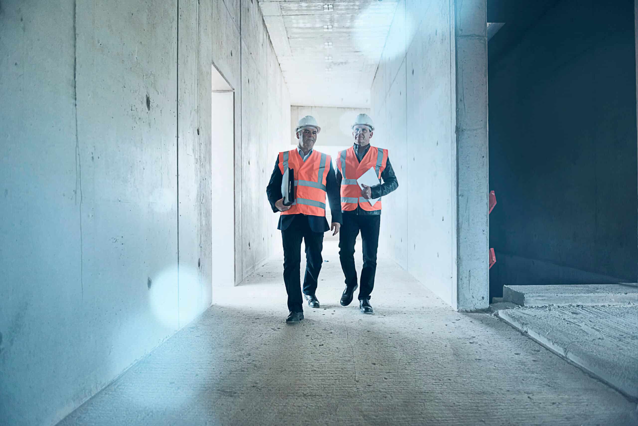 Two men wearing safety walking in building under construction